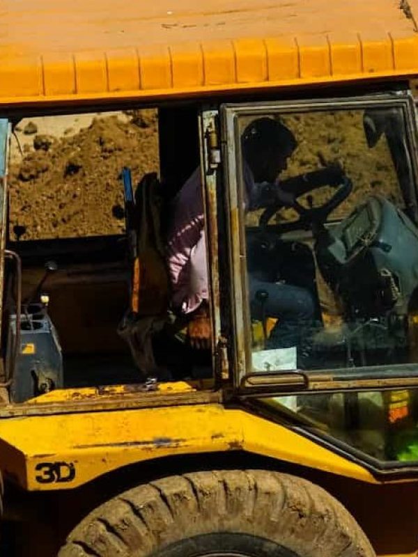 Close-up of a man driving a yellow bulldozer on a construction site during the day.